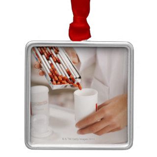 Pharmacist in drug store measuring pills into christmas tree ornaments